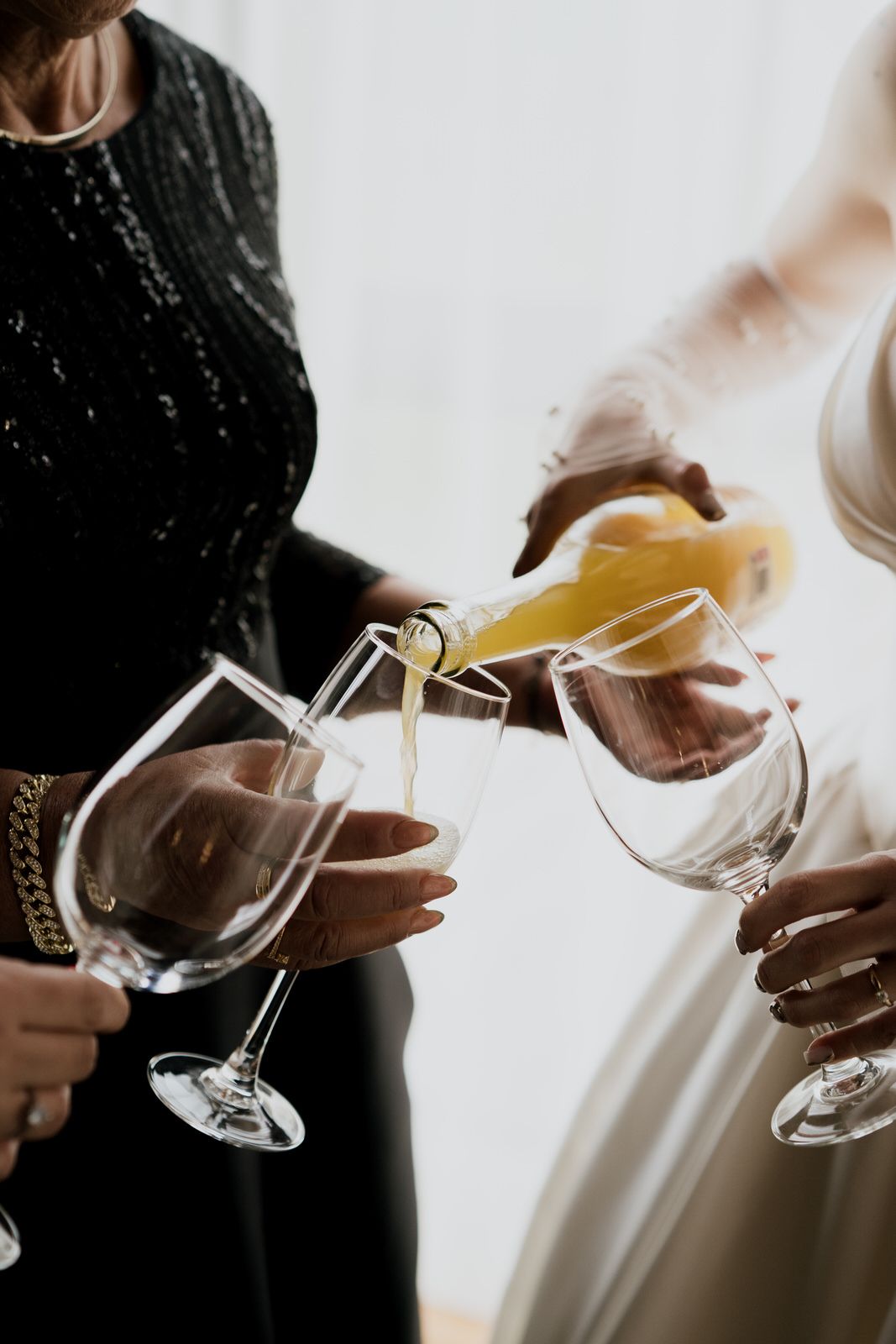 Hands pouring white wine into crystal glasses during formal event.