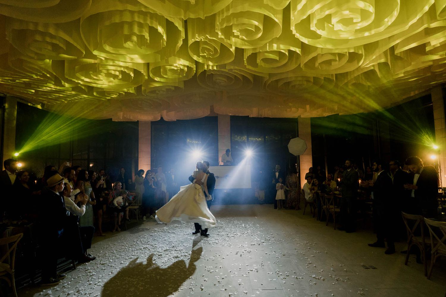 Yellow lighting creates a warm ambiance during a wedding reception dance.