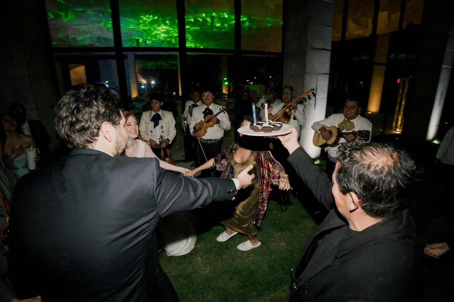Wedding celebration in full swing with green lighting and dancing guests.