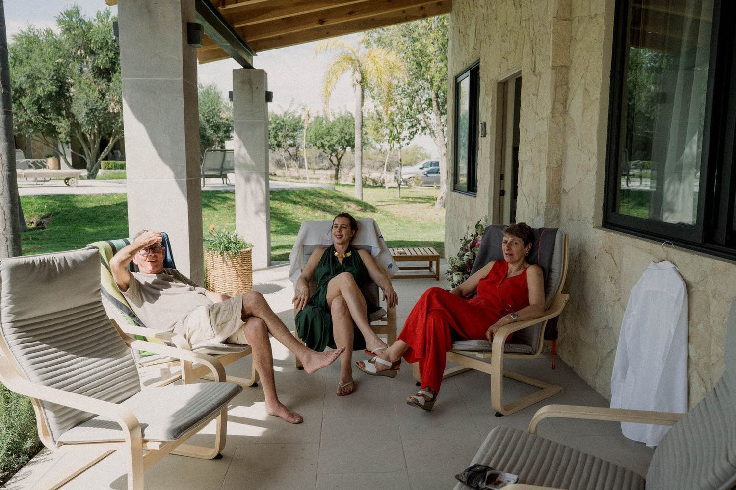 Group of people relaxing on a covered outdoor patio with wooden beams and brick walls.