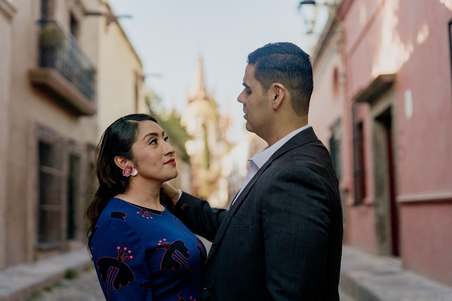 A romantic moment captured in a charming colonial street with pink walls.