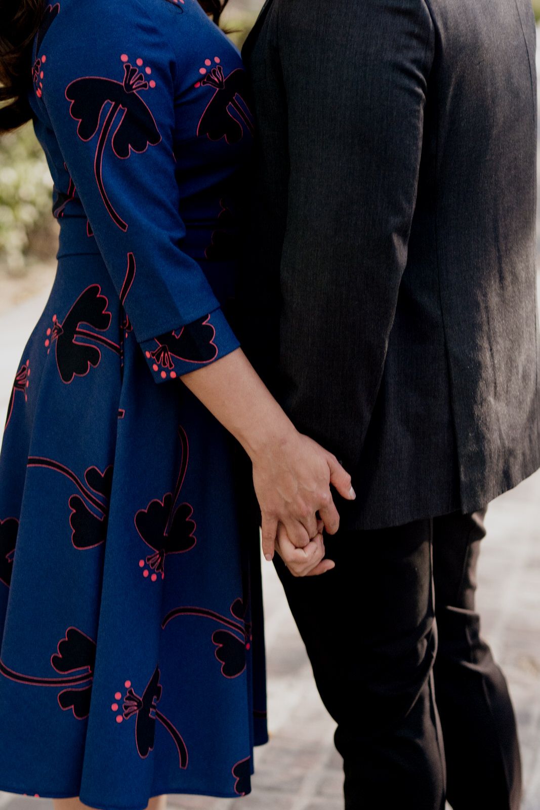 Close-up of formal attire showing navy blue dress with floral pattern next to dark suit.