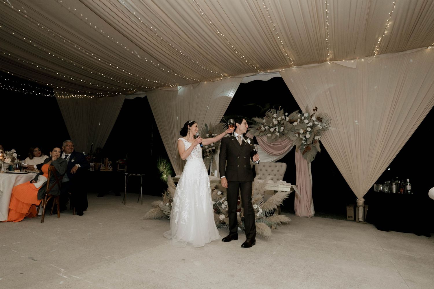 Wedding venue decorated with white draping and filled with dramatic lighting effects.