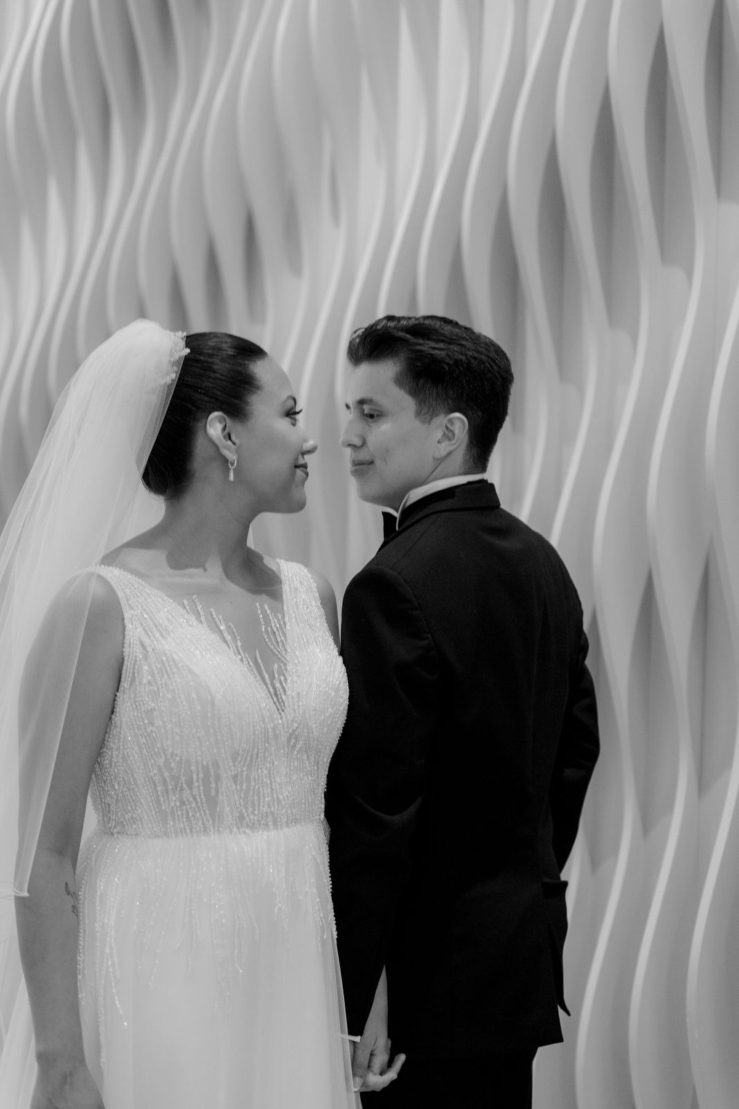 Black and white portrait of bride and groom gazing at each other at wedding.