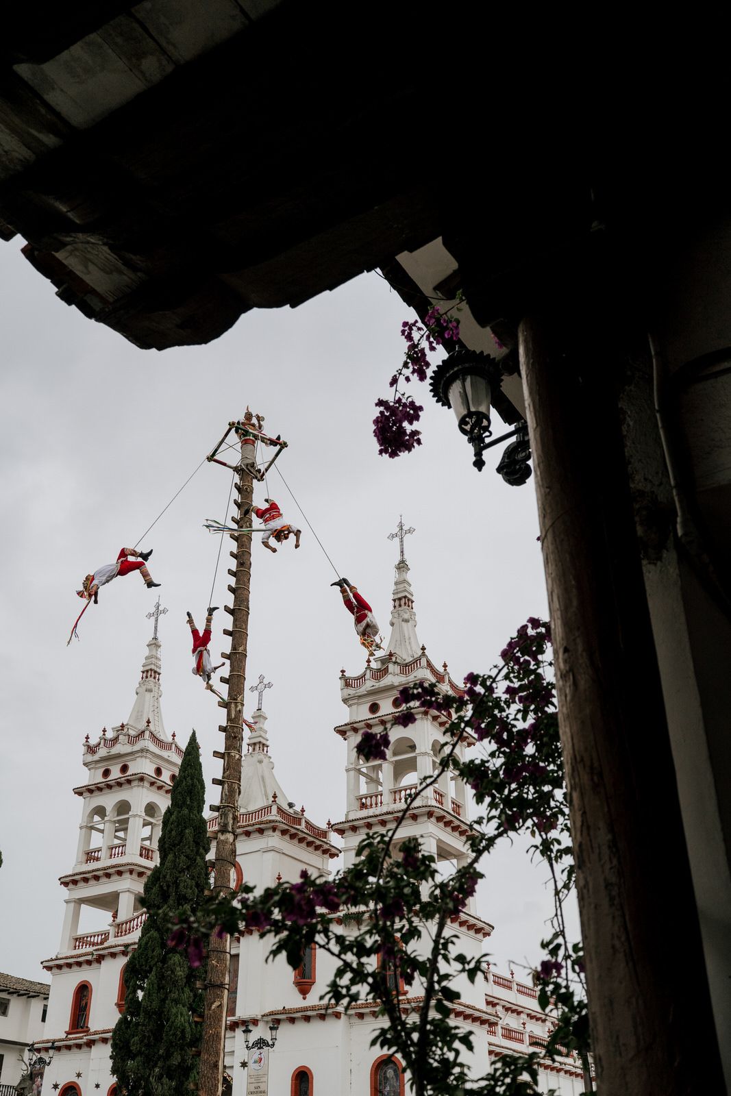 Decorative red and white banners hang between white church towers against an overcast sky.