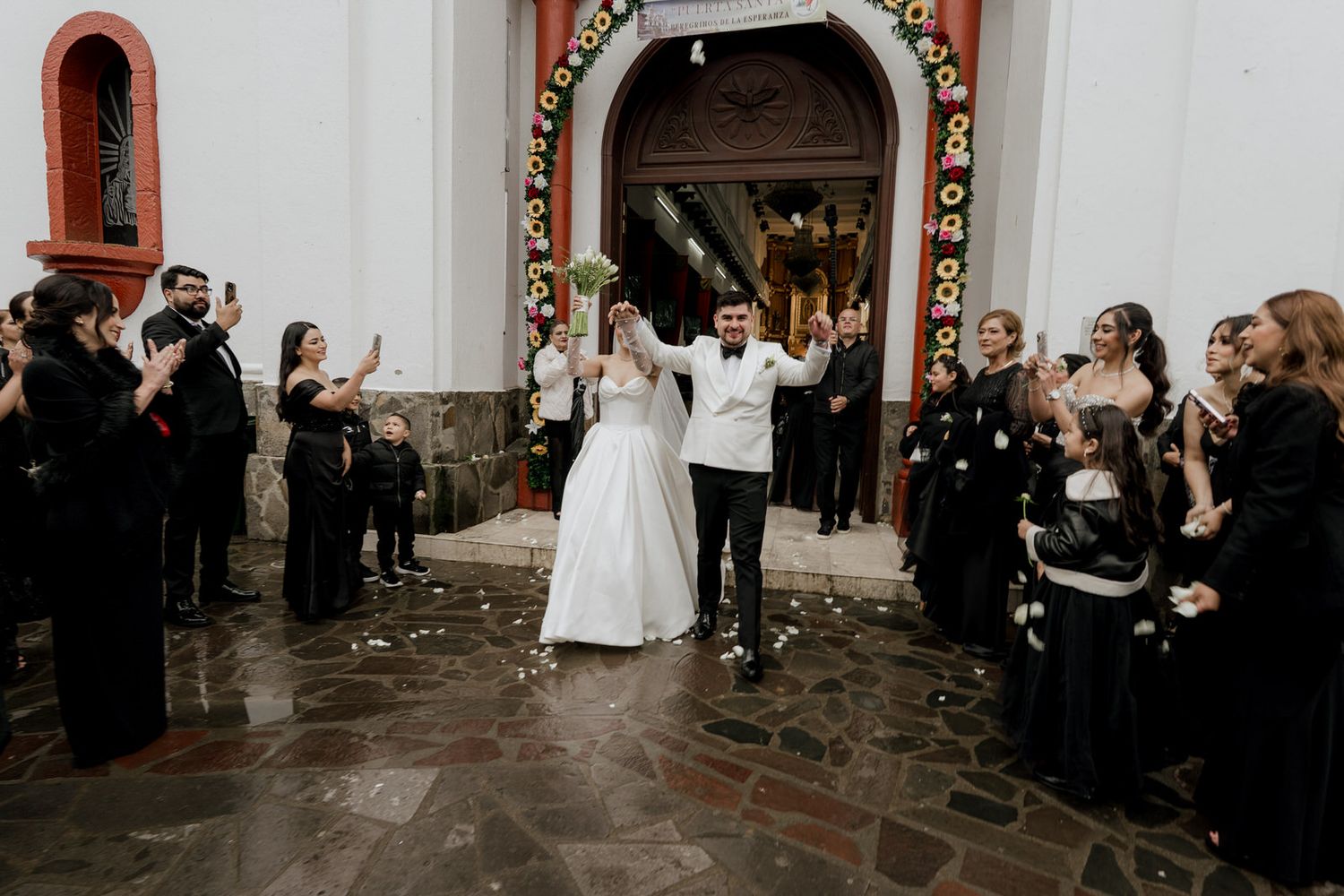 Wedding guests line the aisle of a church during the ceremony exit.