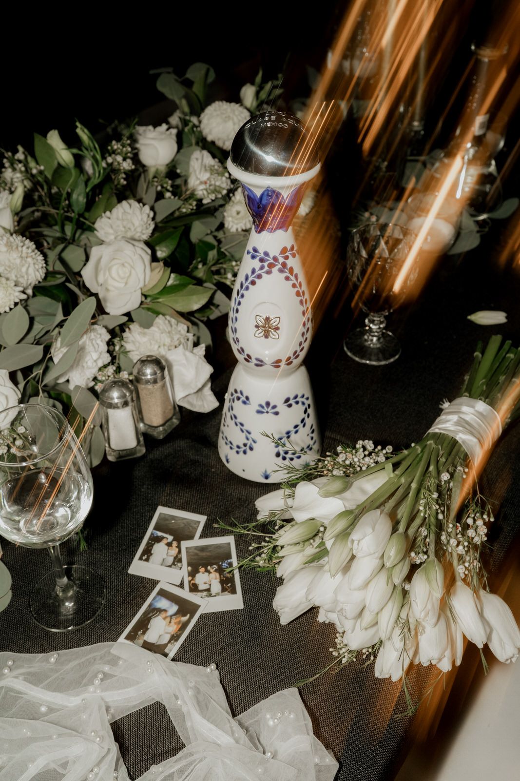 Elegant white floral centerpiece with candles and decorative details on dark table surface.