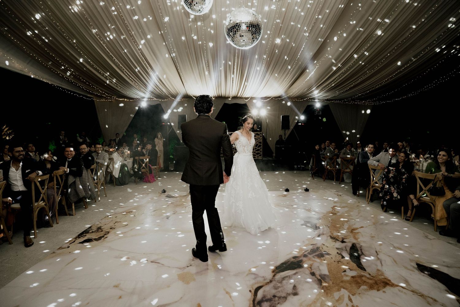 Wide shot of a wedding reception venue with sparkling lights and elegant white draping.