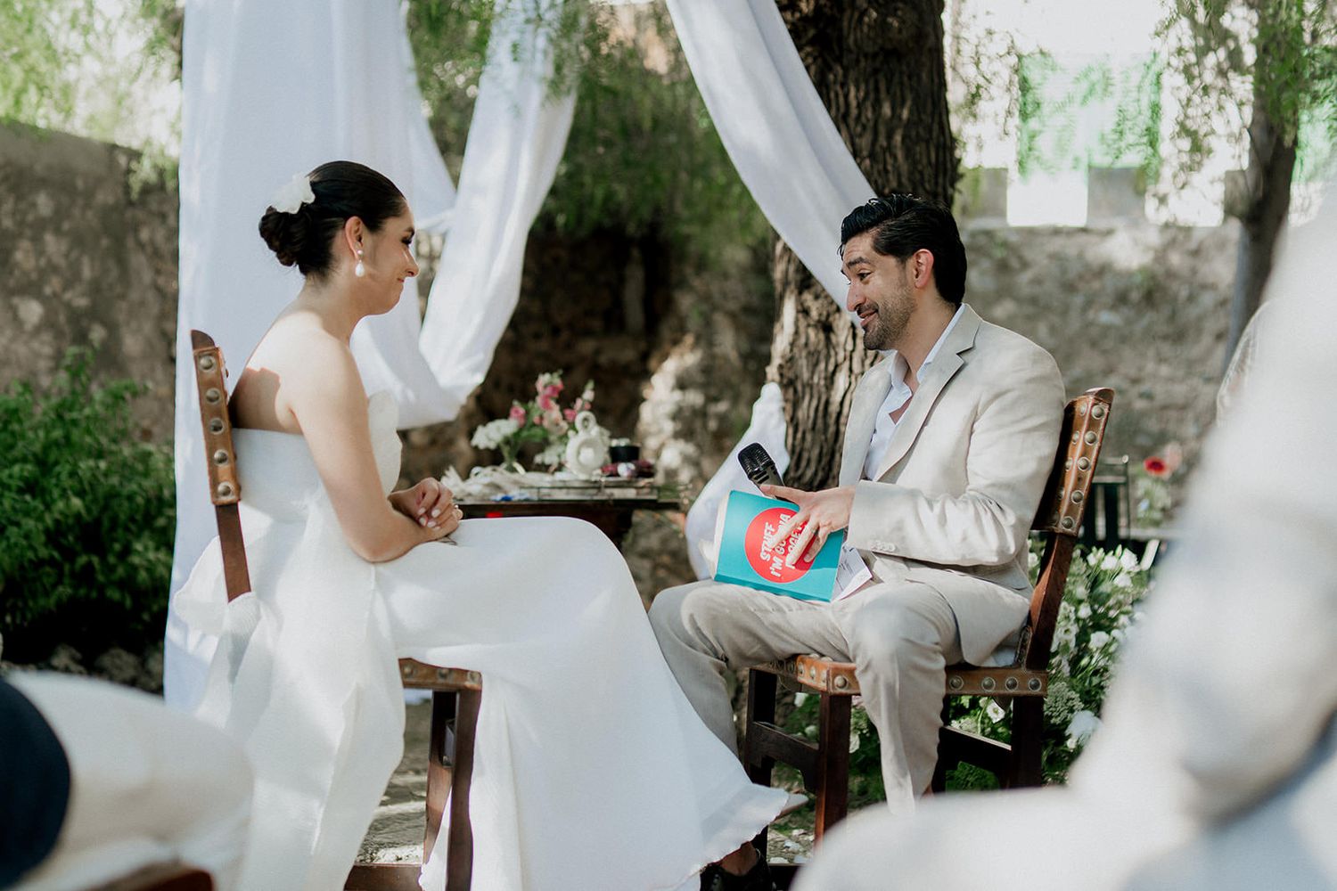 White fabric drapes create an elegant outdoor wedding setting among trees.