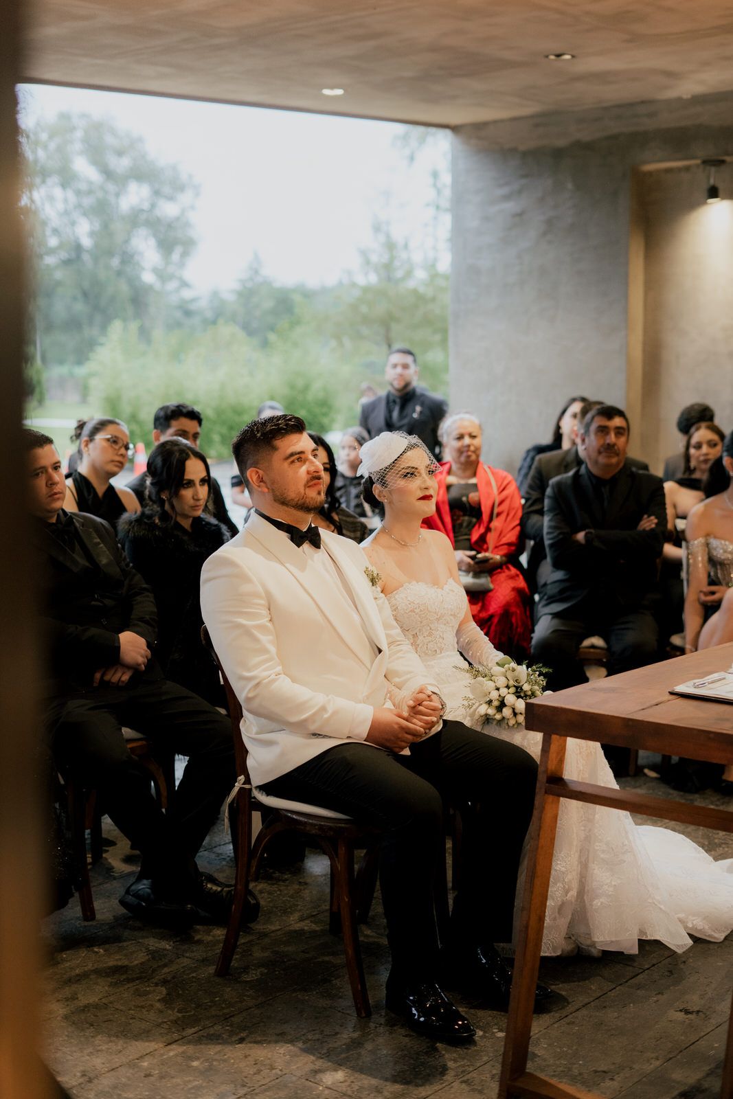 Wedding ceremony in contemporary concrete venue with guests watching proceedings.
