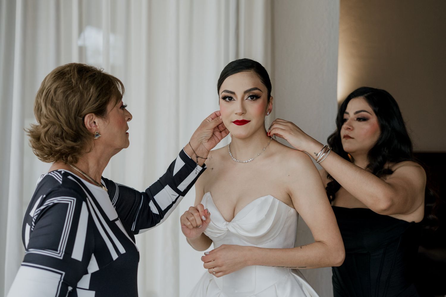 Wedding preparations in a bright room with white curtains and elegant gown.