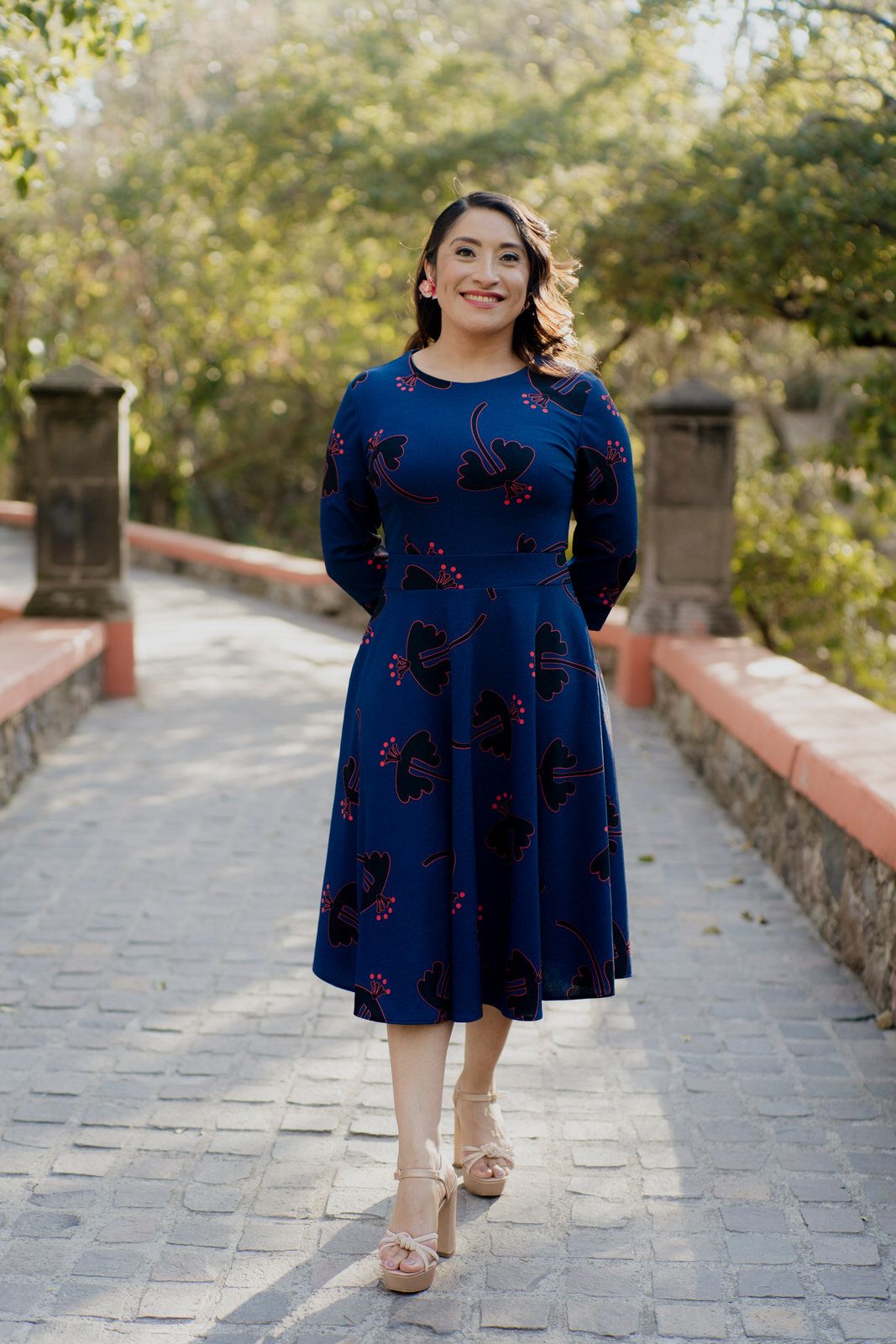 A woman in a flowing navy dress walks along a stone pathway.