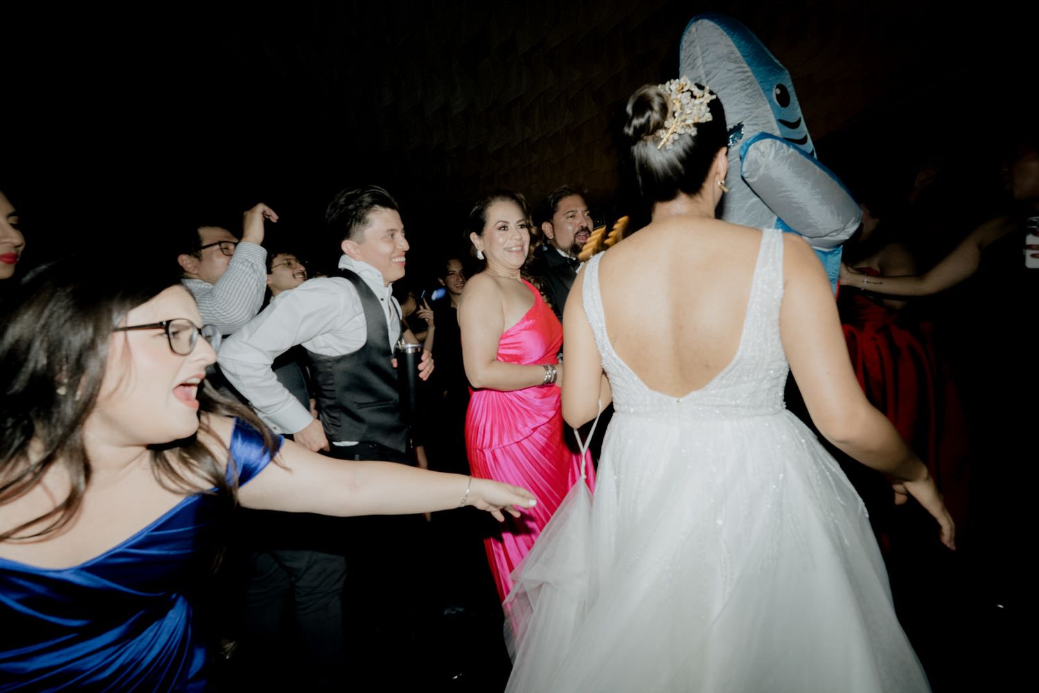 Guests dancing at a wedding reception, featuring a bride in a white gown and friends in colorful dresses.