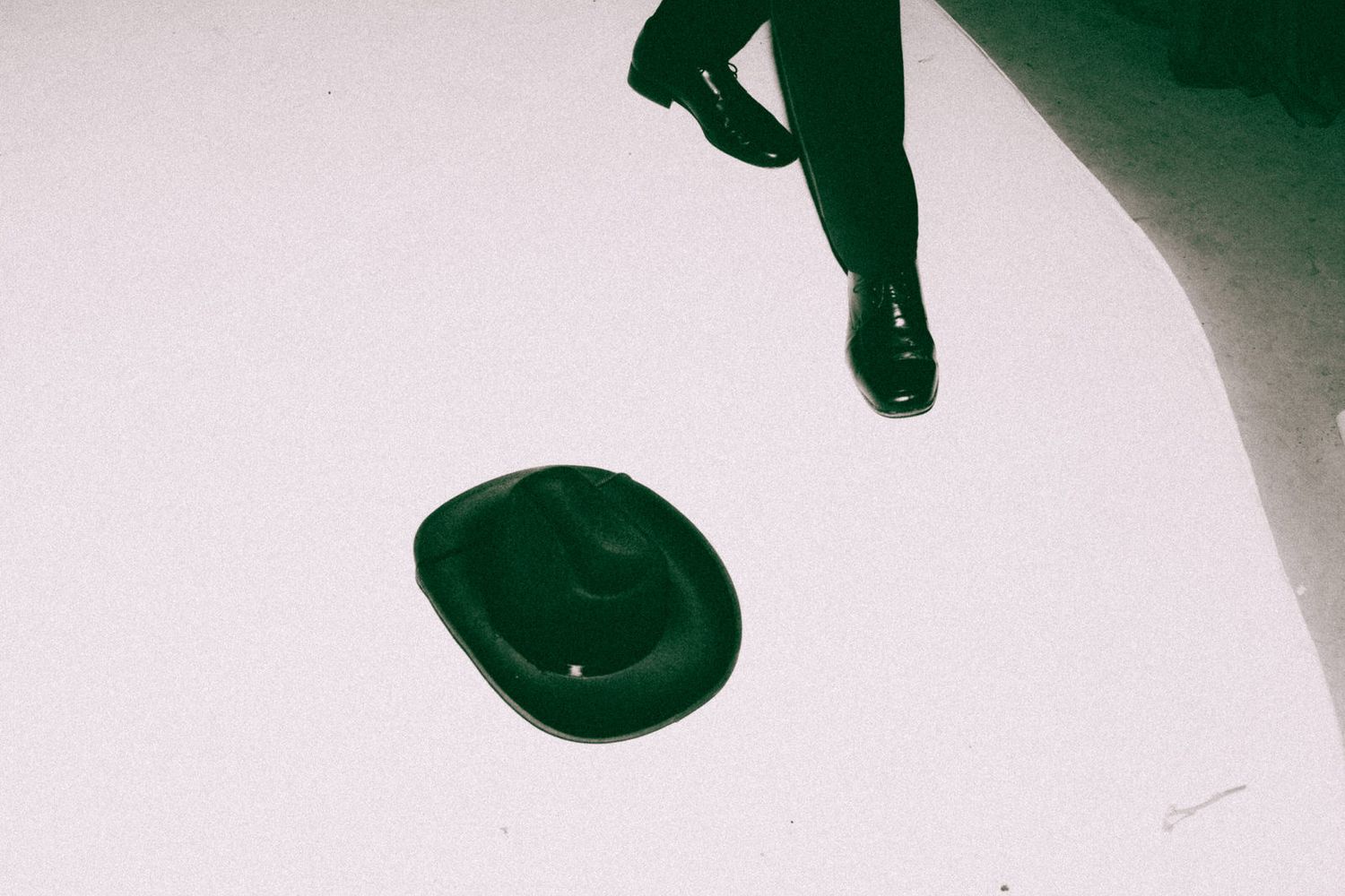 Minimalist artistic photo of dress shoes and hat shadow on white background.
