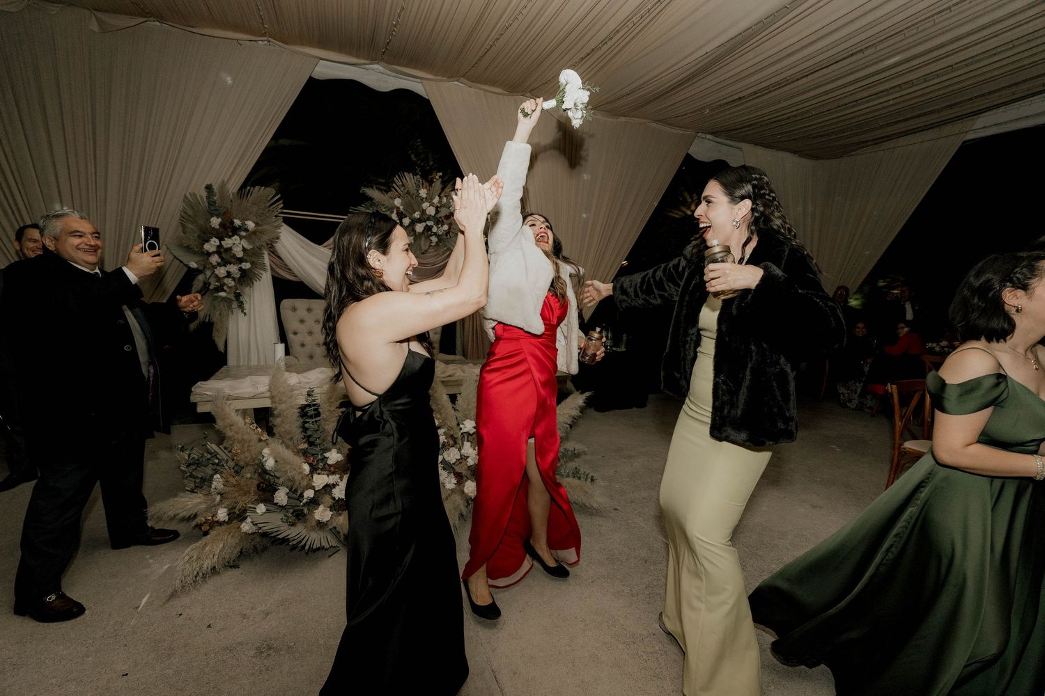 Festive wedding reception with guests dancing beneath elegant fabric-draped ceiling.