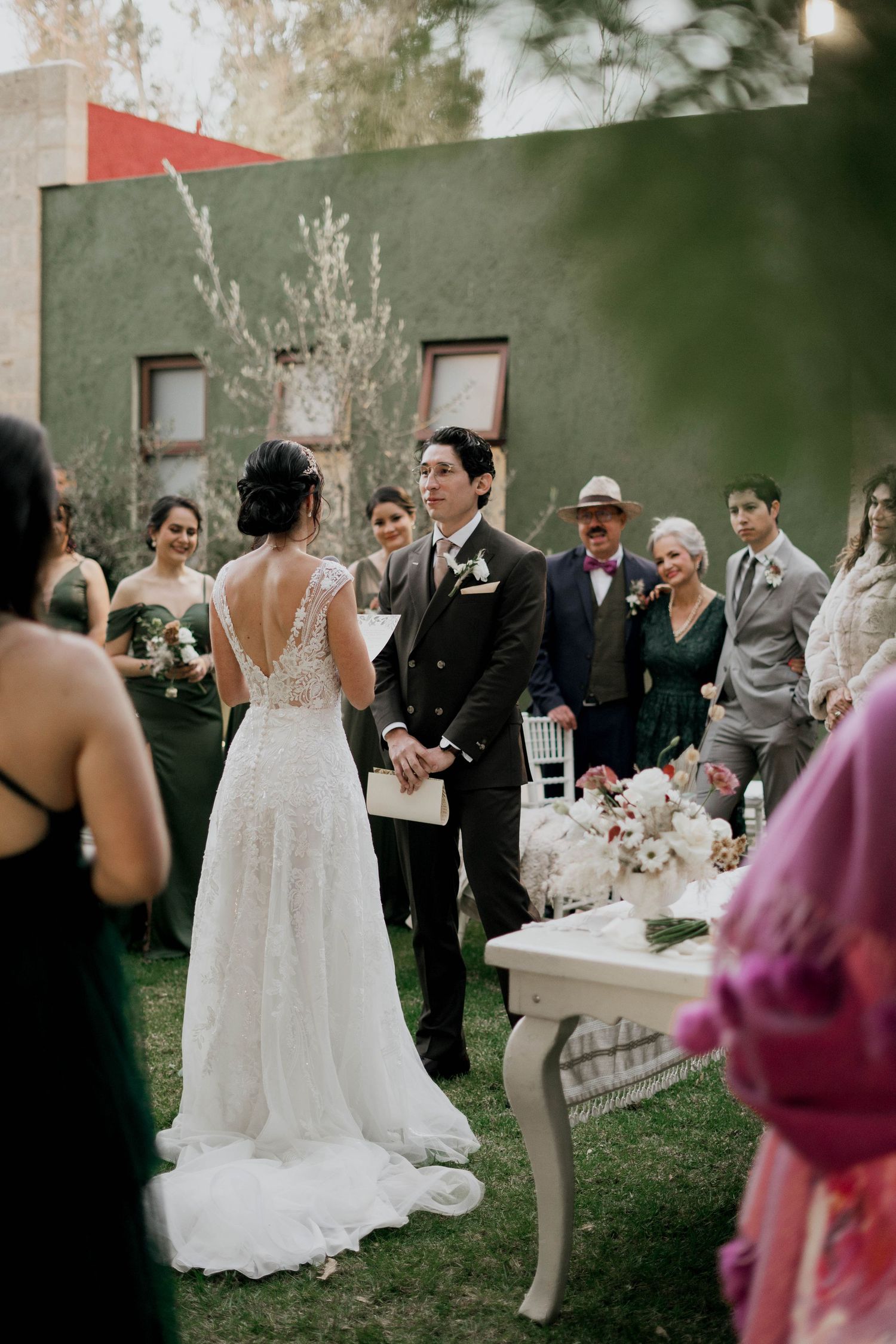 Elegant outdoor wedding reception with white gowns and stone wall backdrop.