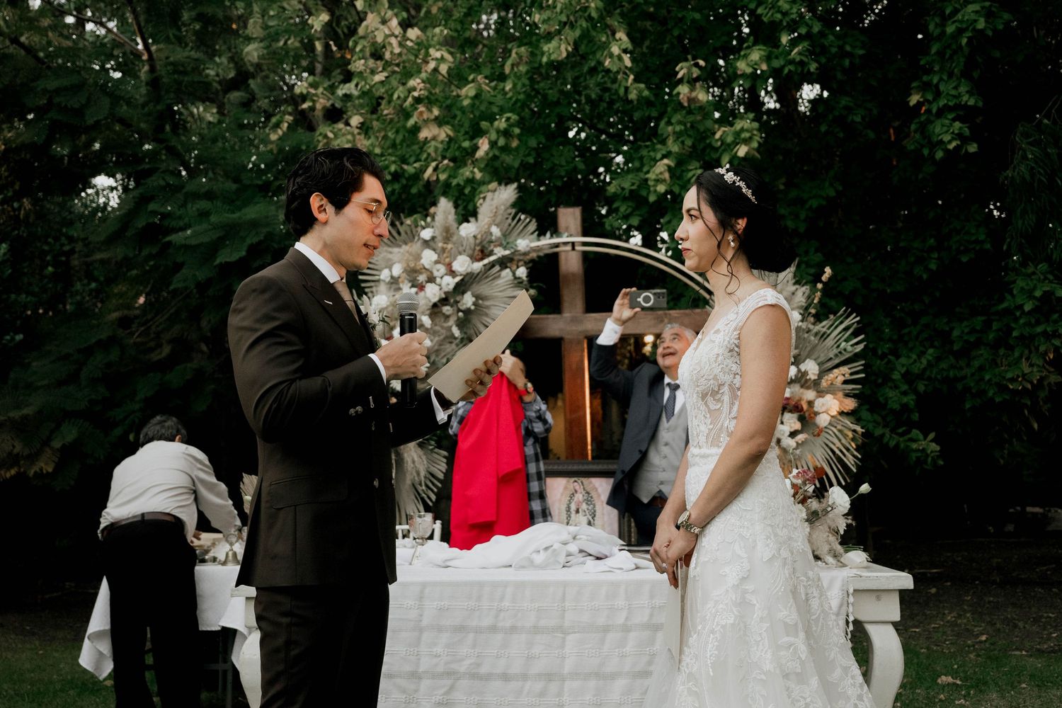 Elegant outdoor wedding reception setup with white decor against stone walls.
