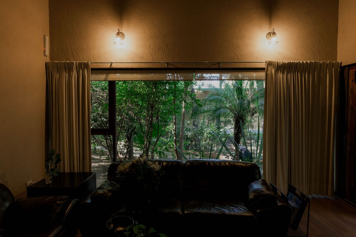 Living room interior with large window overlooking lush forest scenery.