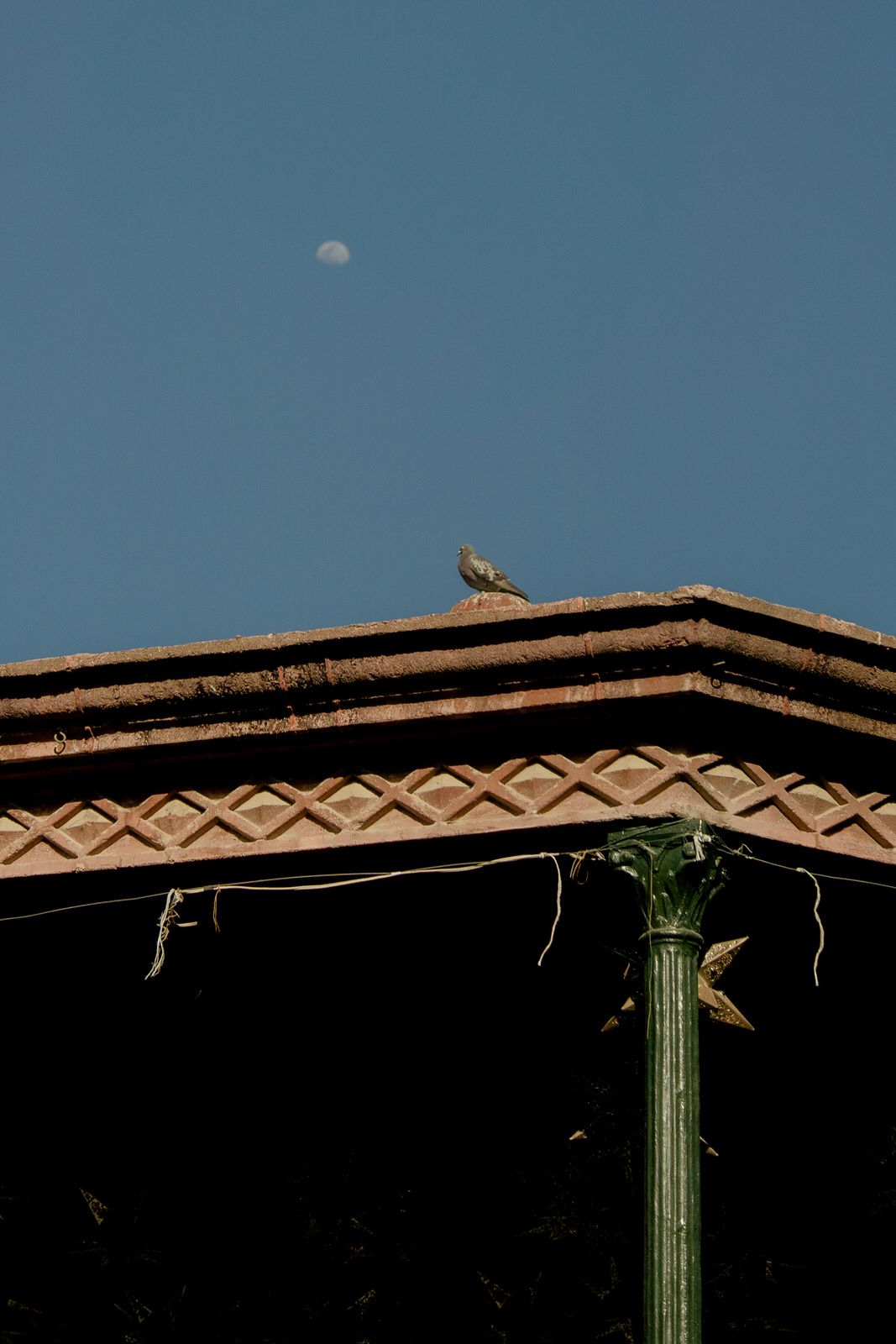 Decorative roofline with green column detail against blue sky.