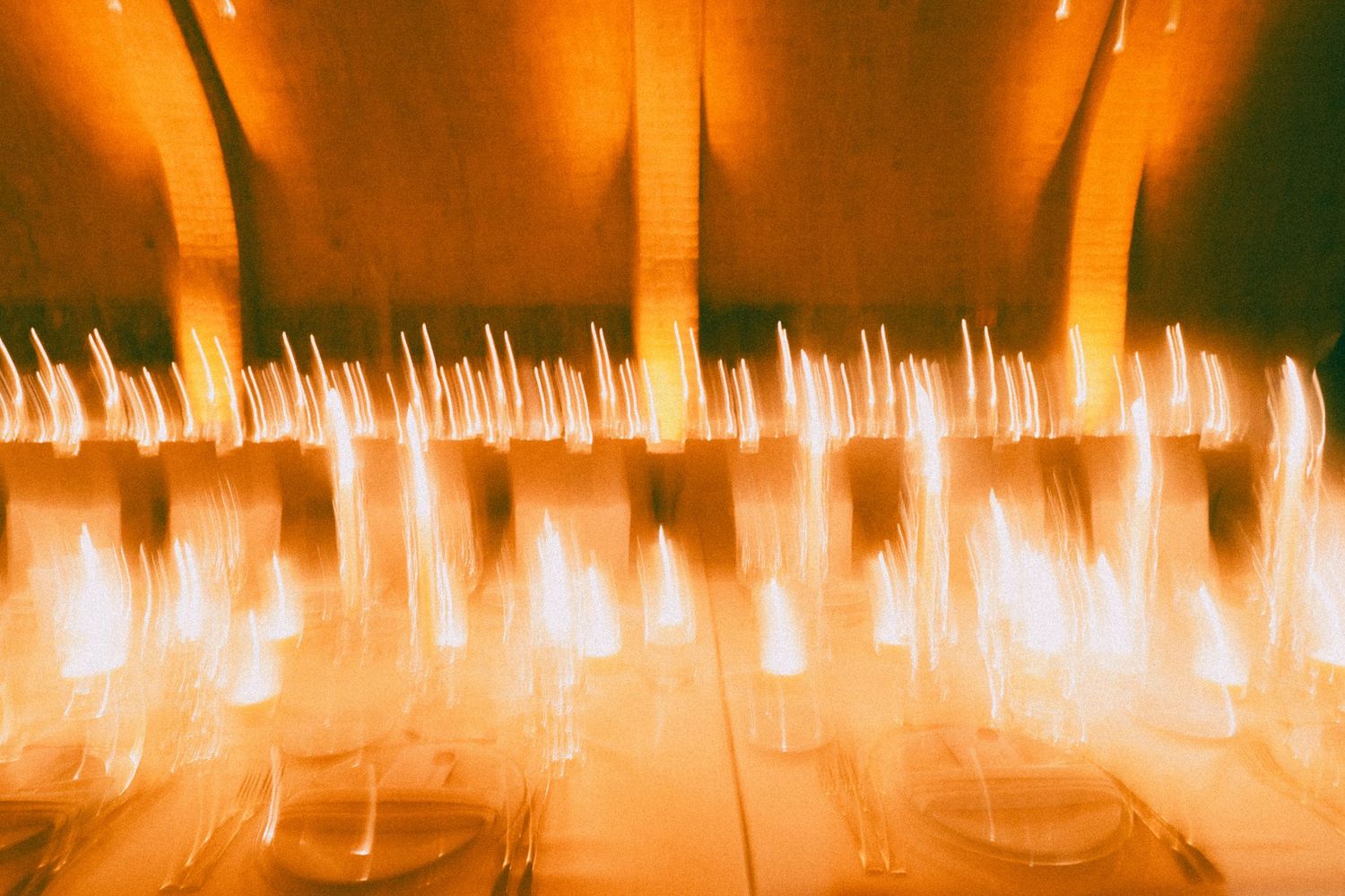 Elegant candlelit wedding reception venue with arched brick ceiling and dramatic lighting creating a romantic atmosphere.