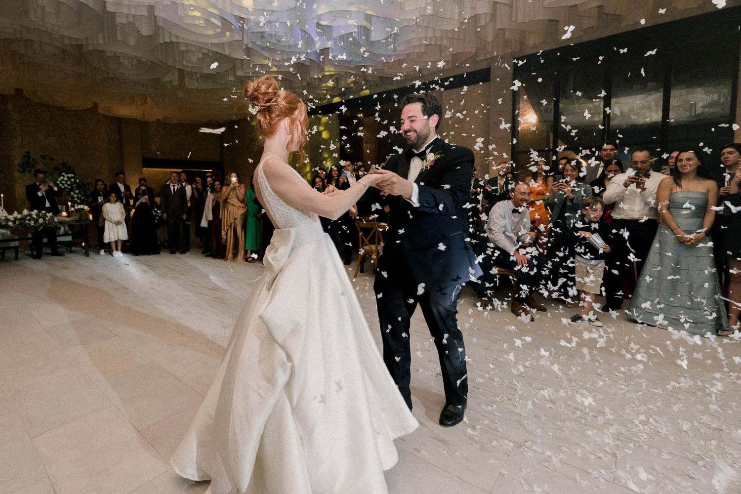 White confetti falls as a couple dances in the center of their wedding reception.