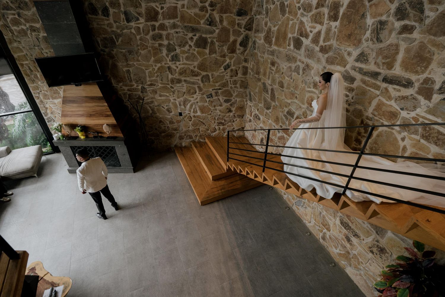 Architectural view of wooden staircase against stone wall in modern interior space.