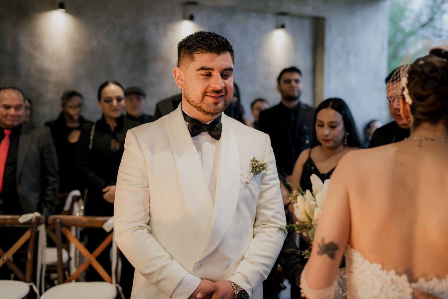 Wedding ceremony in contemporary venue with industrial concrete ceiling and elegant decor.