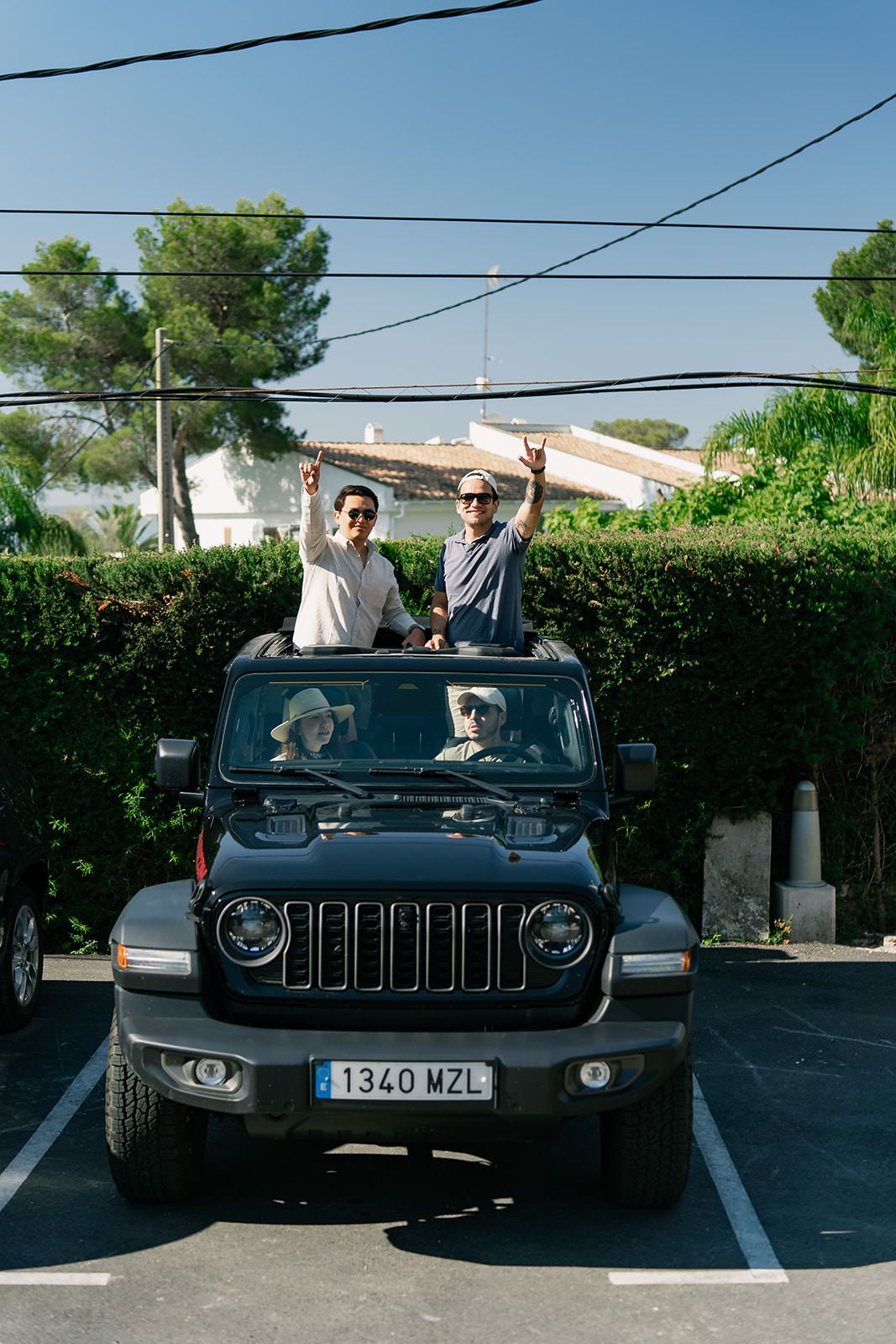 Three views of a black Jeep Wrangler parked in a lot with green hedges and power lines visible in the background.