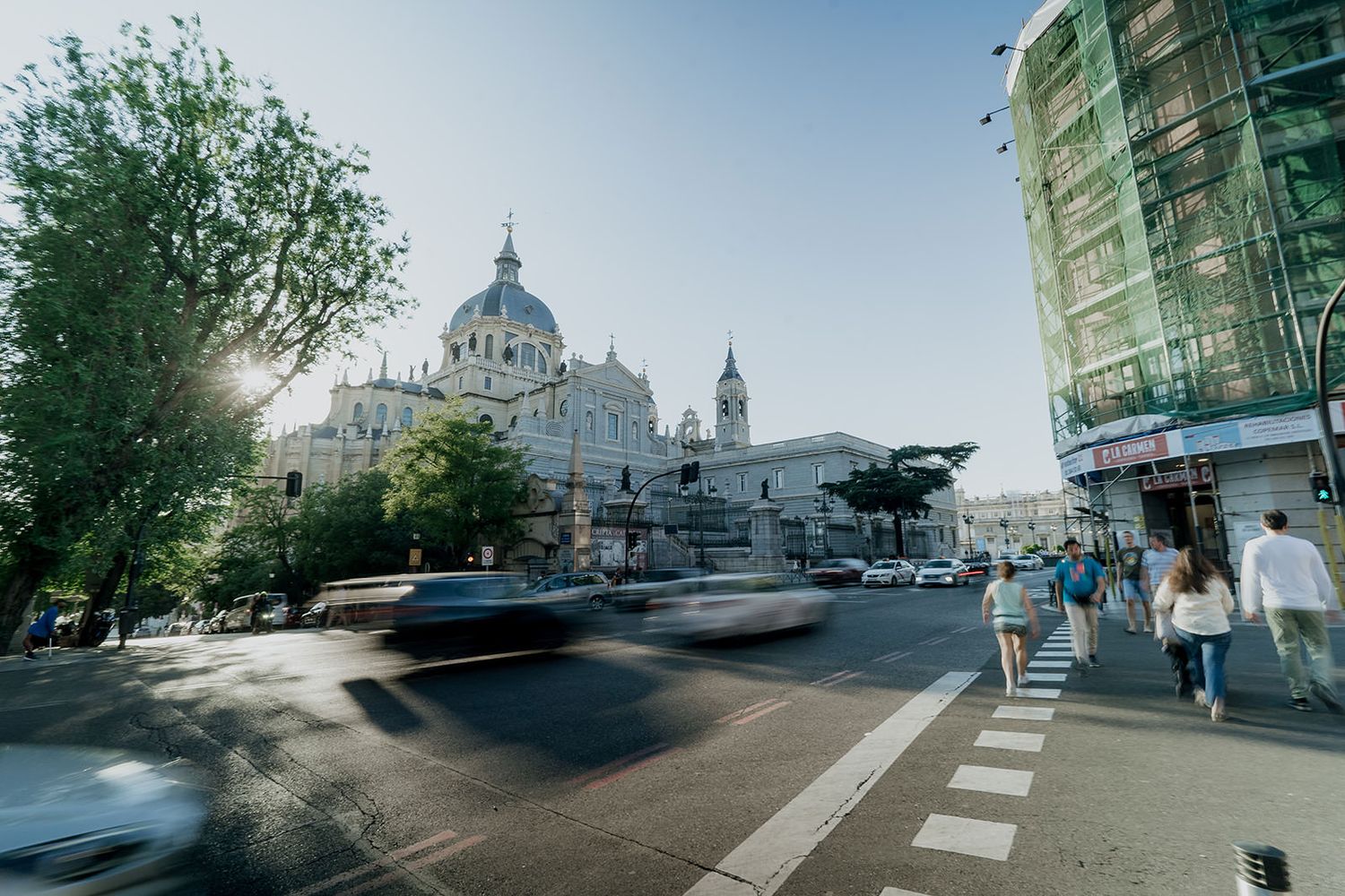 Panoramic view of a European city street with historic architecture and domed buildings in the distance.
