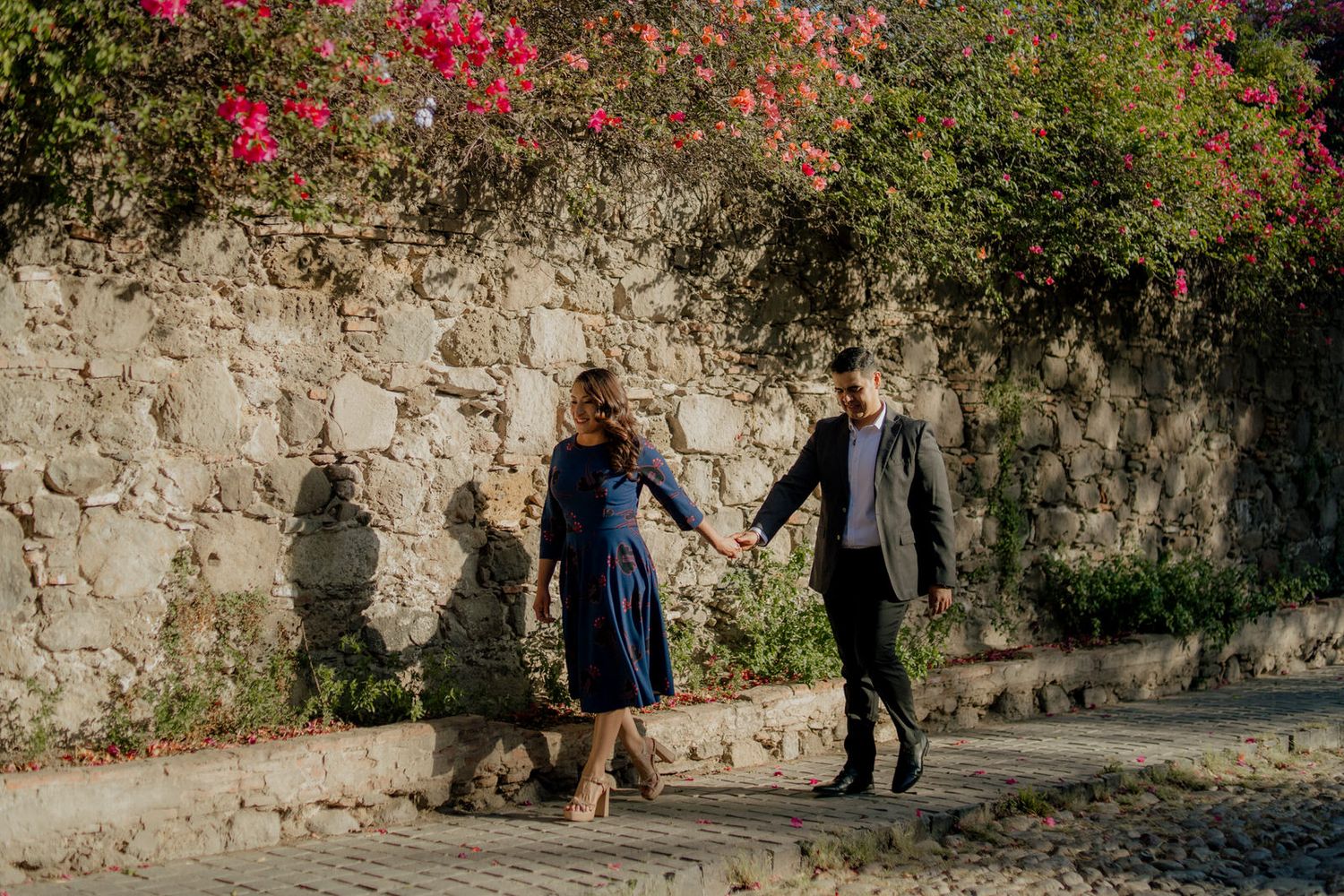 Stone wall with cascading pink flowers creating romantic garden backdrop.