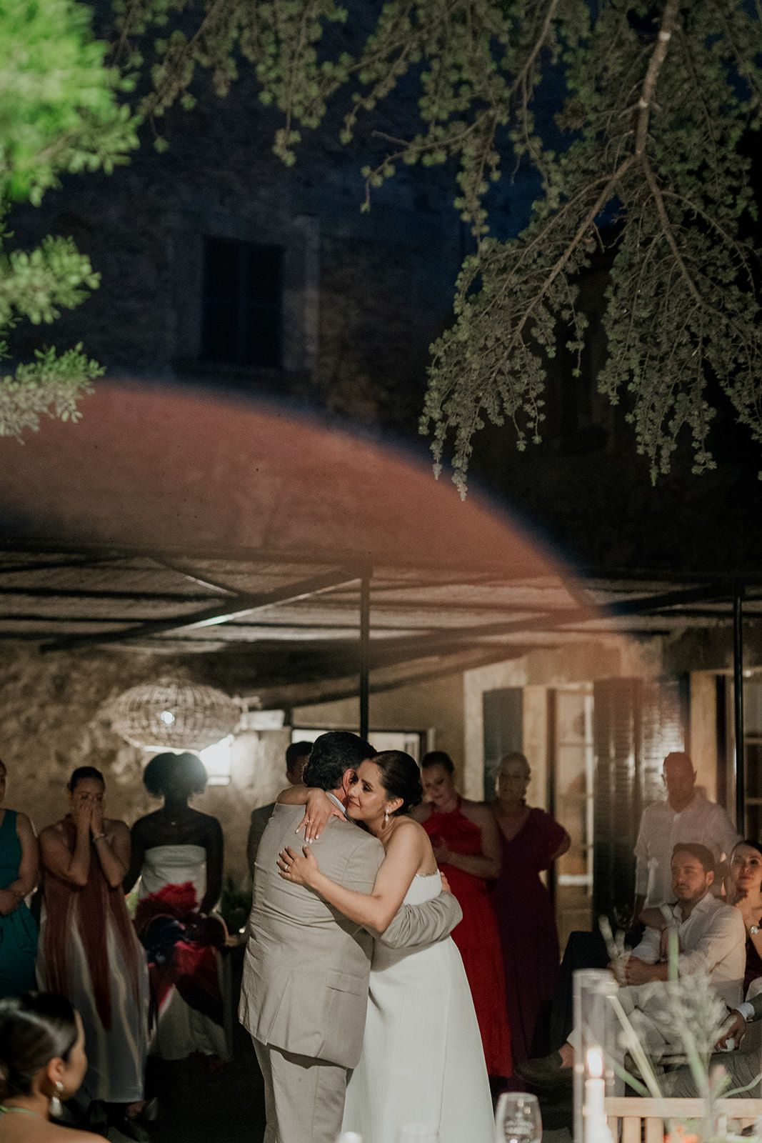 A romantic first dance sequence captured at a wedding reception under a covered outdoor venue with string lights.