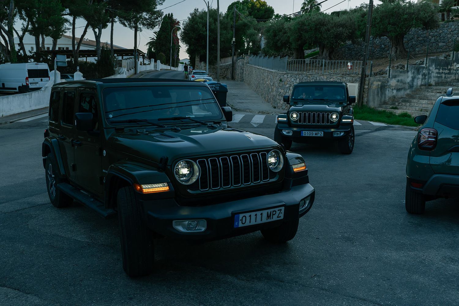 Row of parked Jeep vehicles along a street in evening light.