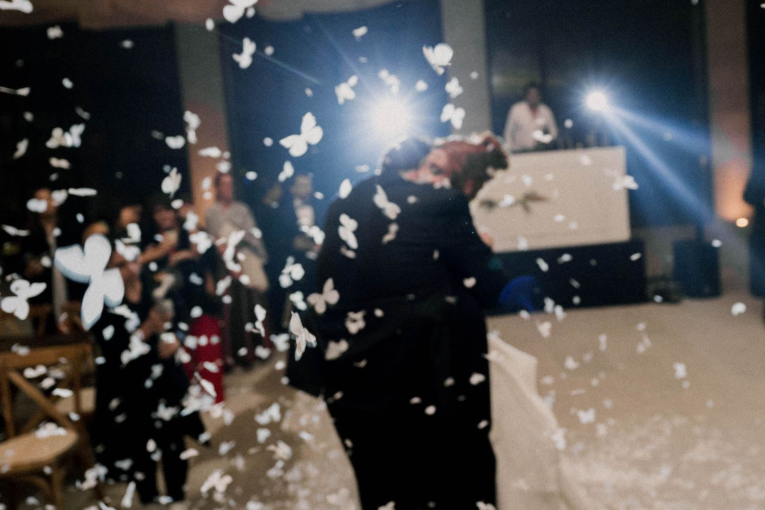 White confetti falls through dark air at a party celebration with blue lighting effects.