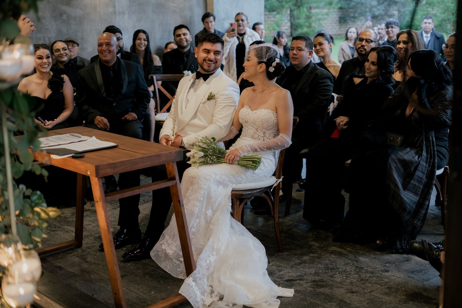 Wedding celebration in modern indoor space with guests seated at wooden tables.