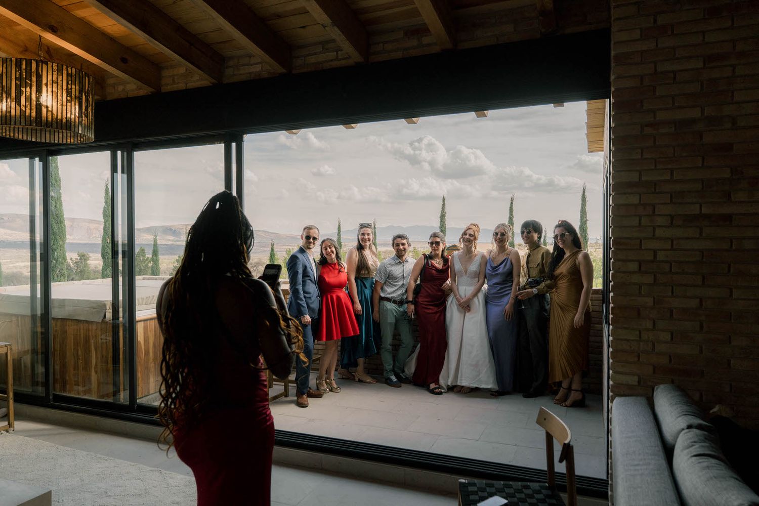Wedding party poses together in an industrial-style venue with natural lighting.