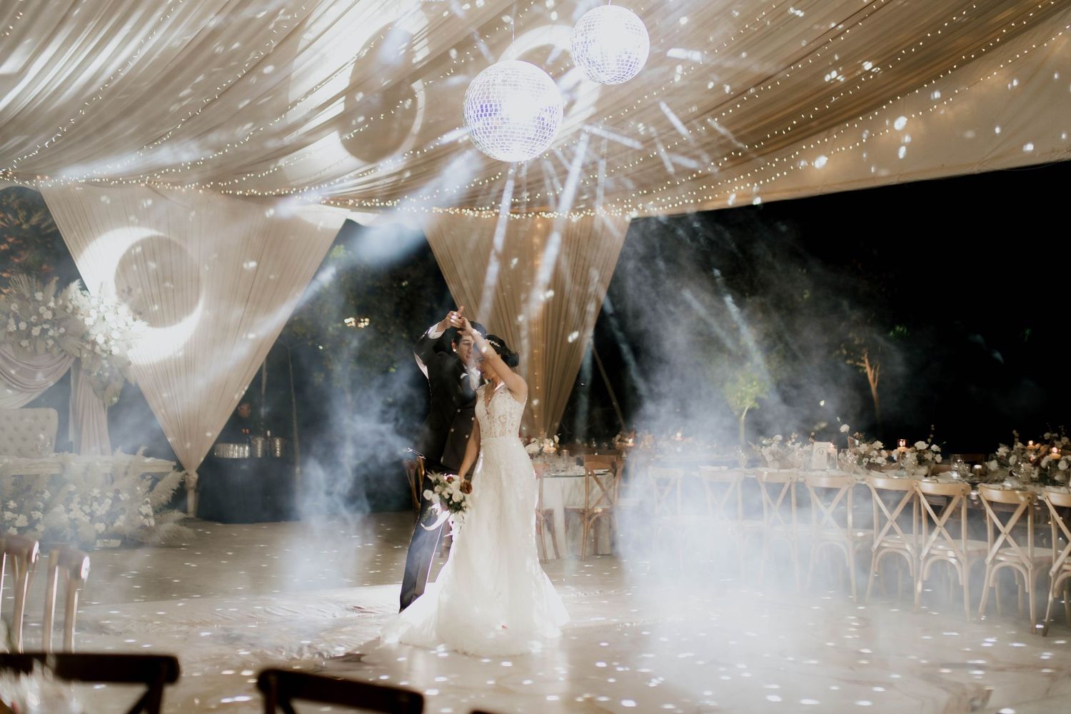 Atmospheric event space with smoke effects, string lights and white draping creating a dreamy ambiance.