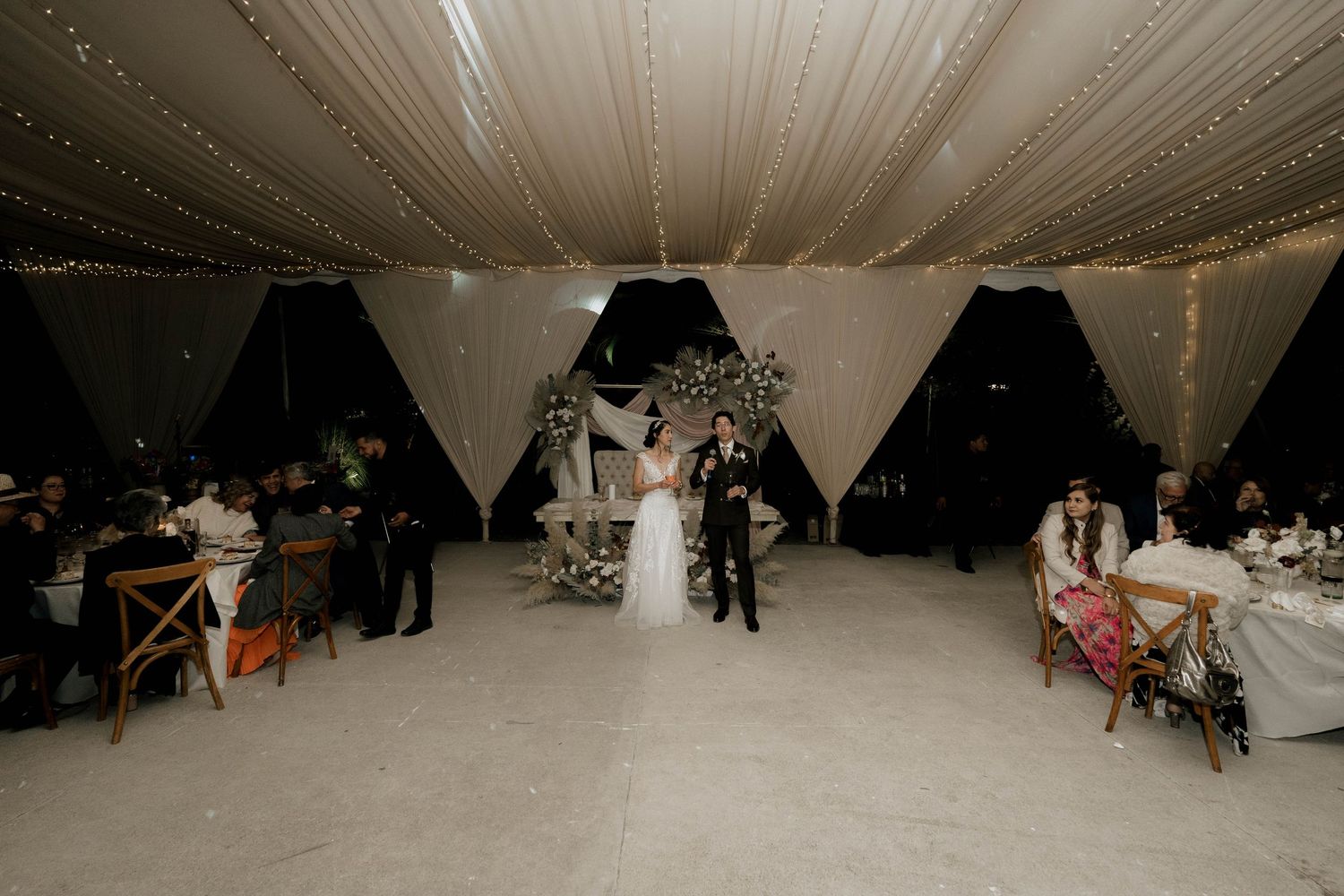 Wedding reception space with elegant ceiling draping and dramatic lighting design.