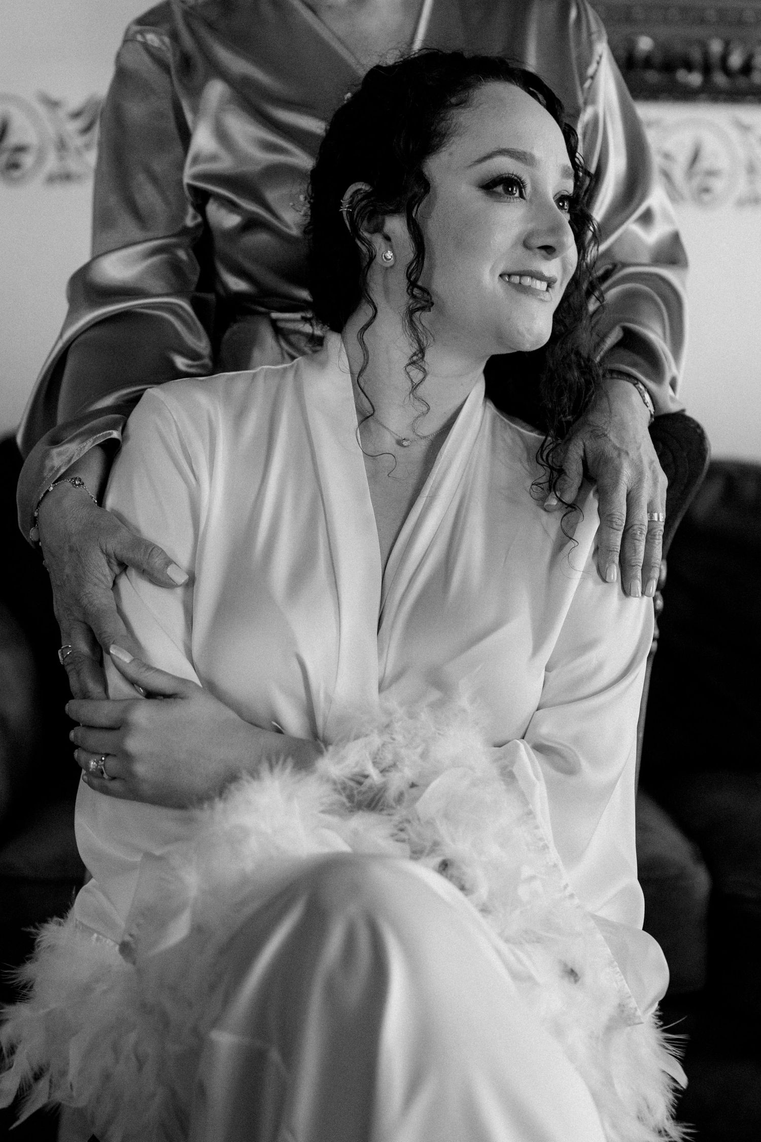 Getting ready scene with white silk robe adorned with feather details.