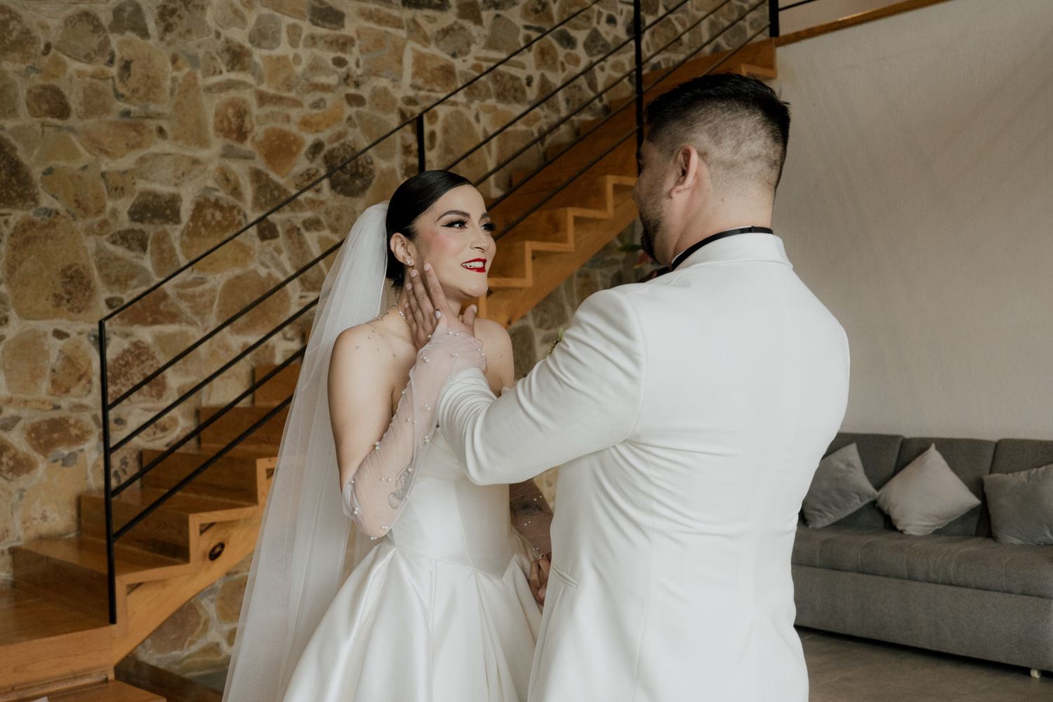 Intimate wedding moment captured in modern venue with stone walls.