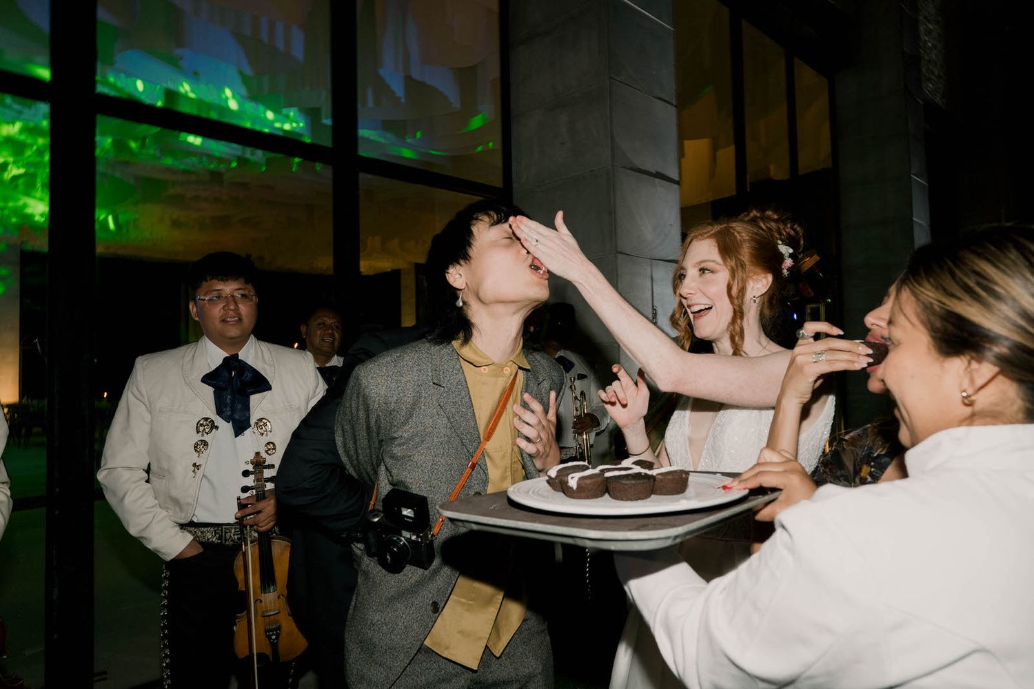 Indoor wedding reception with guests dancing under atmospheric green lighting.