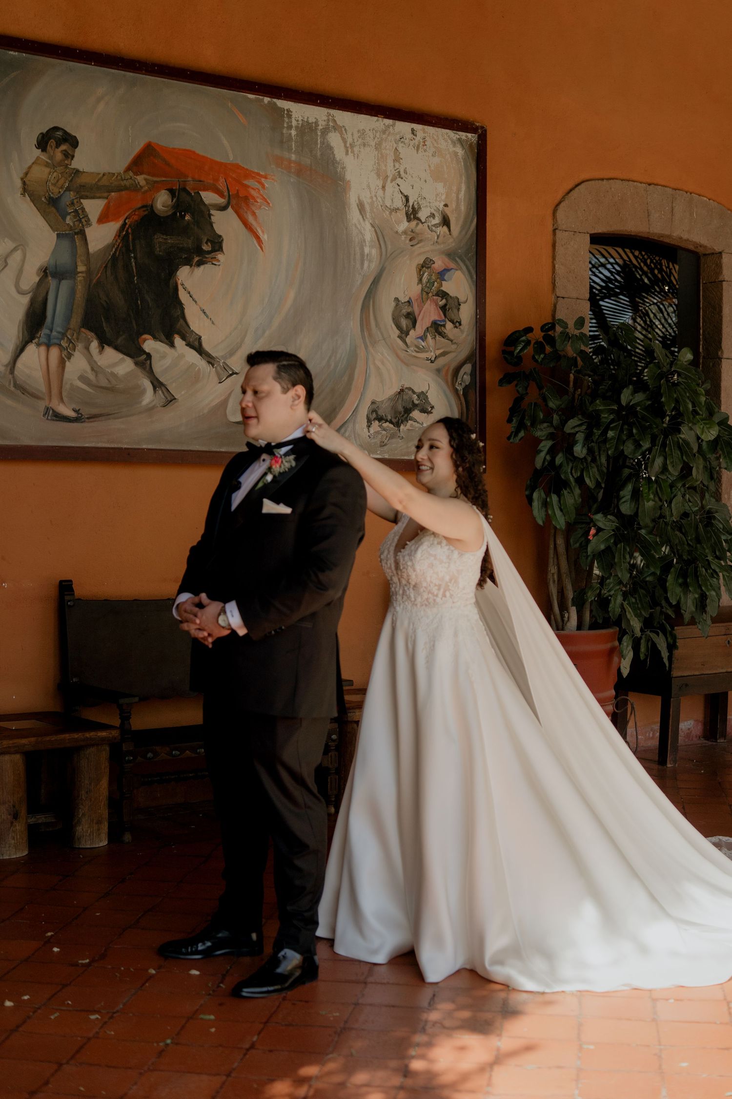 Couple dancing in an elegant venue with terracotta walls and decorative artwork.