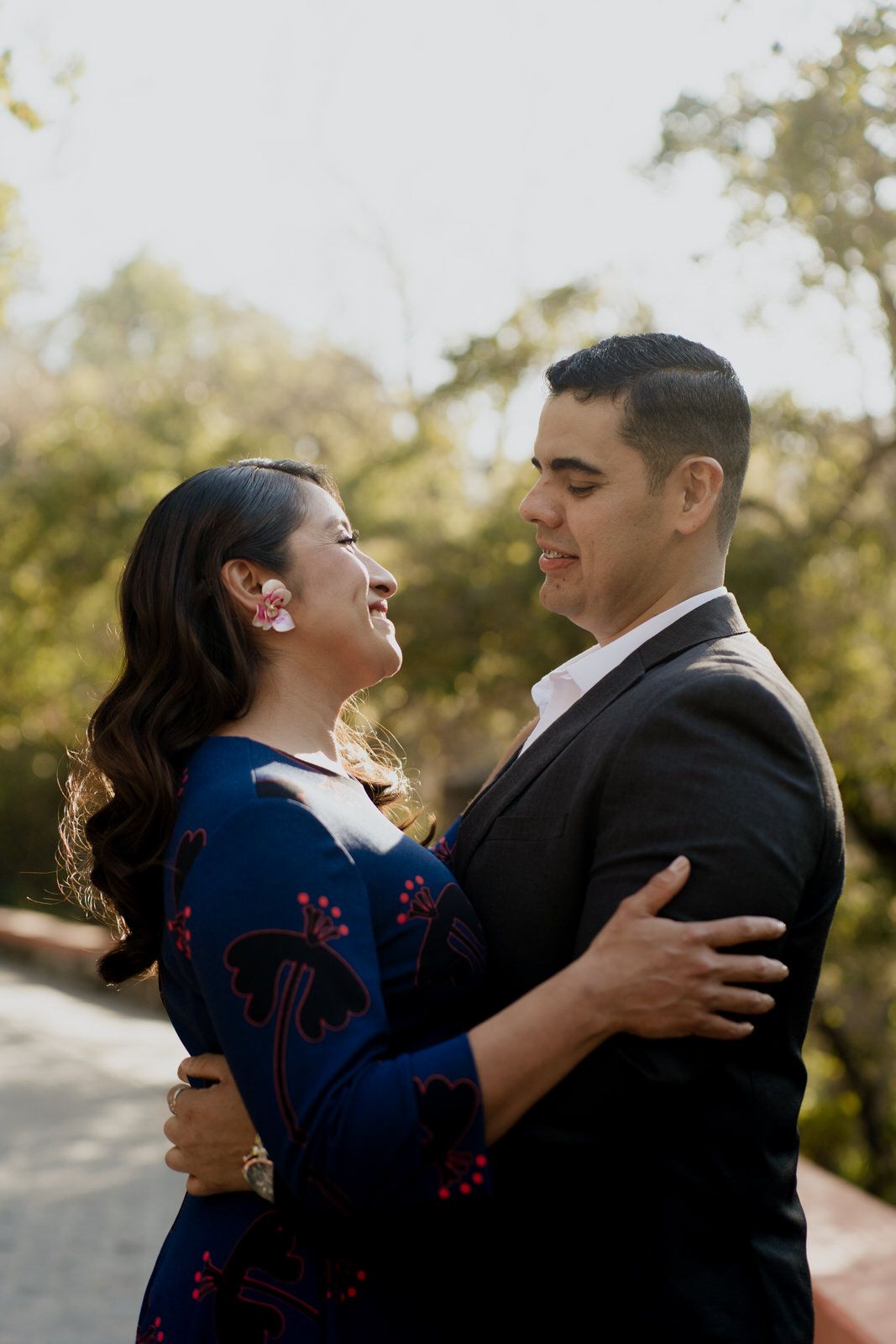 A romantic couple embraces and laughs together during an outdoor photoshoot.