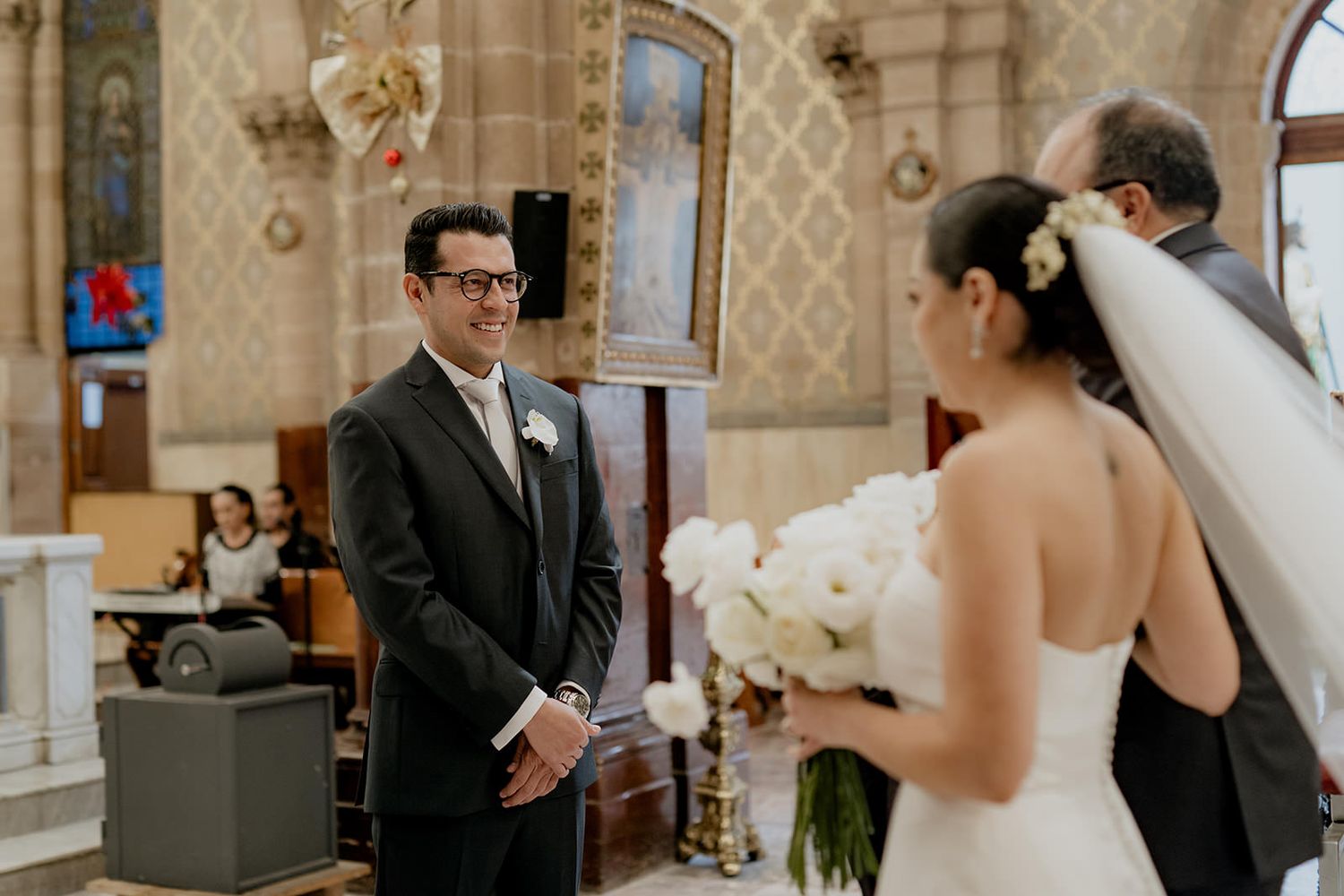 Groom smiles at bride during wedding ceremony inside a beautiful historic church.
