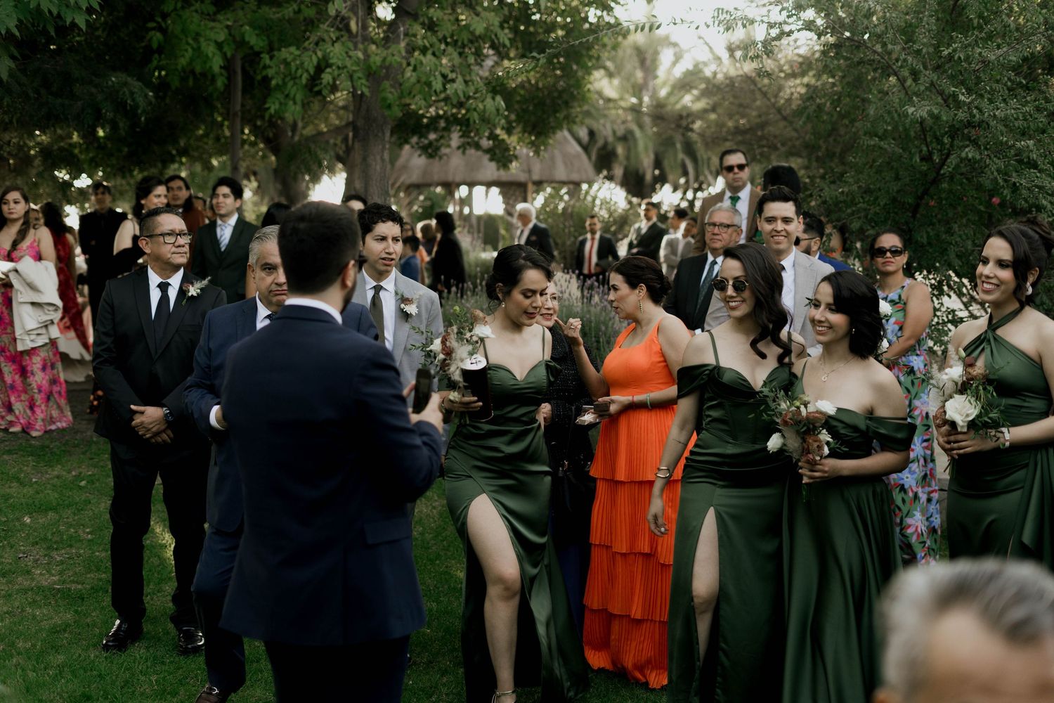 Outdoor wedding gathering with guests mingling on a grassy lawn during cocktail hour.