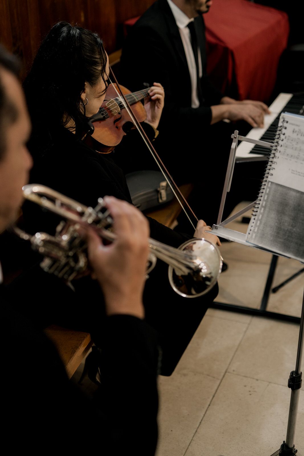 Musicians playing violins at a formal event with sheet music.