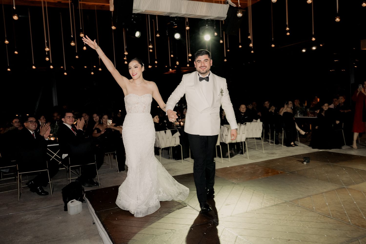 Couples dancing at a wedding reception with dramatic lighting and sparkler effects.