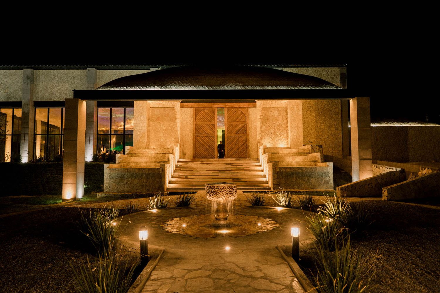Illuminated outdoor venue entrance with warm lighting and architectural features at night.