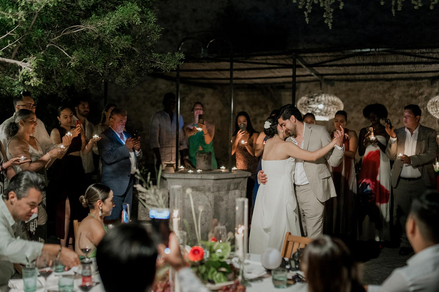 Wedding guests dance and celebrate on an outdoor patio during an evening reception.