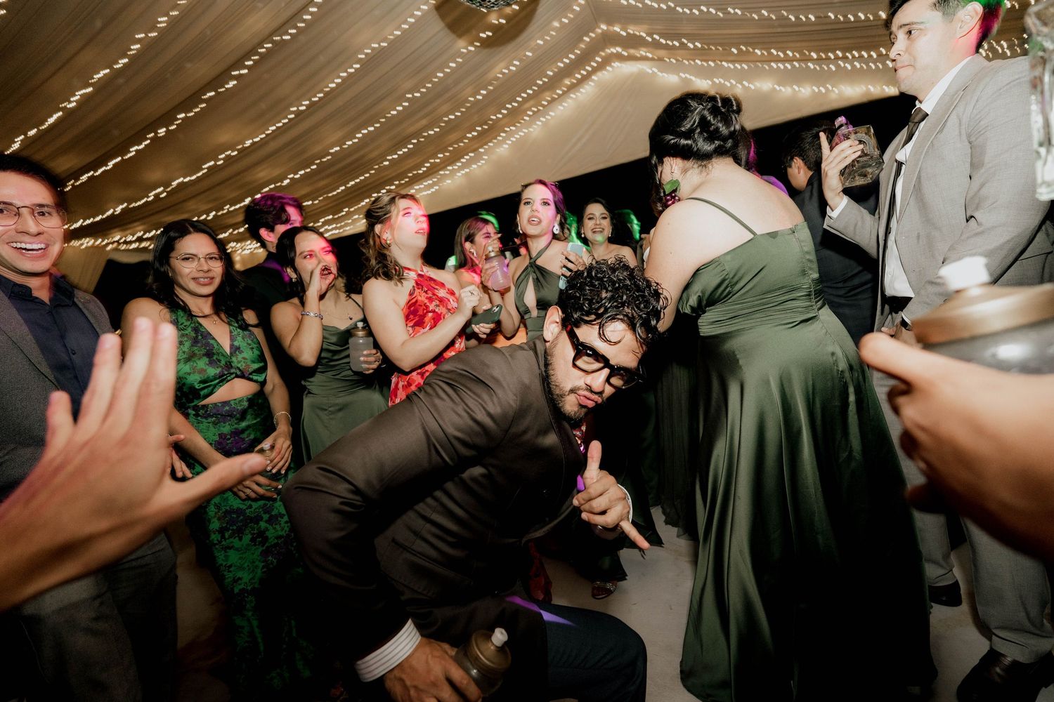Party guests react enthusiastically to someone dancing at wedding reception.