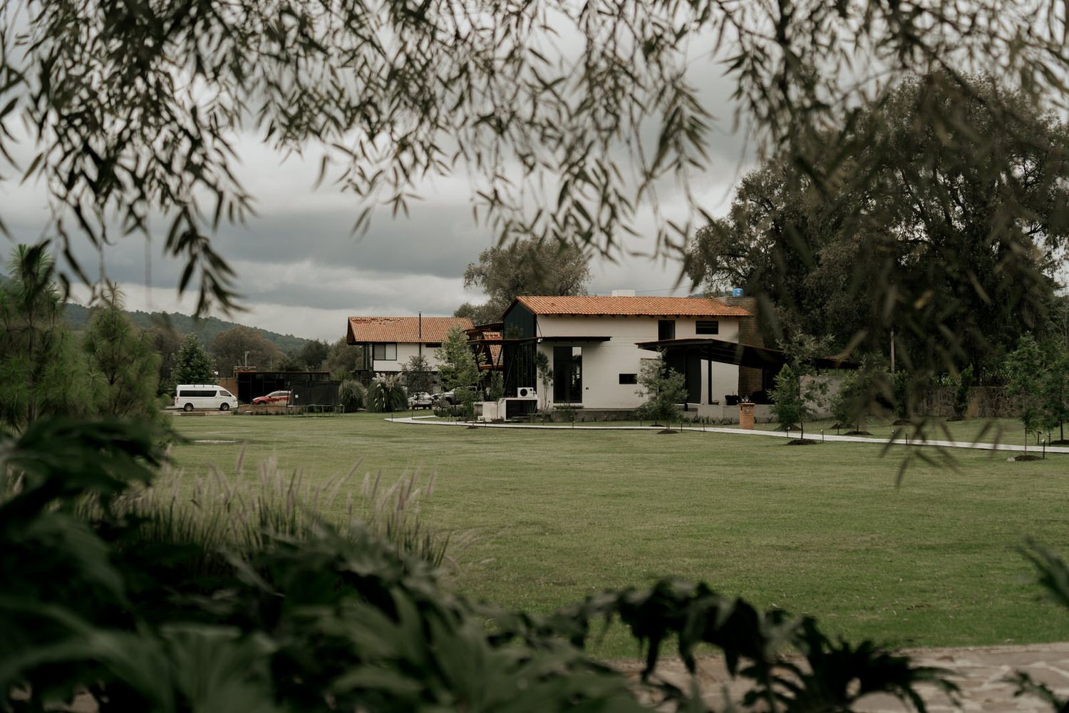 Panoramic view of green fields and distant buildings under cloudy skies.
